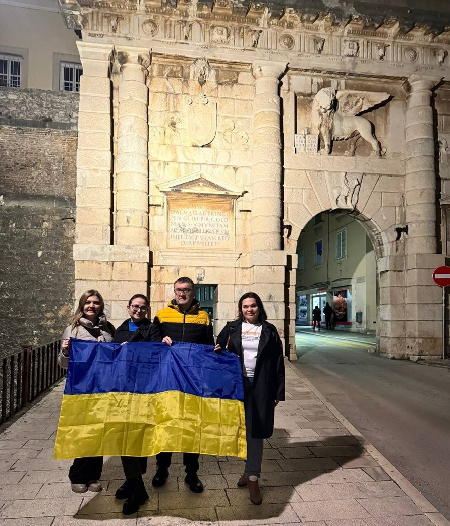 Український прапор з журналістами біля старовинної фортеці  - "Старі ворота"