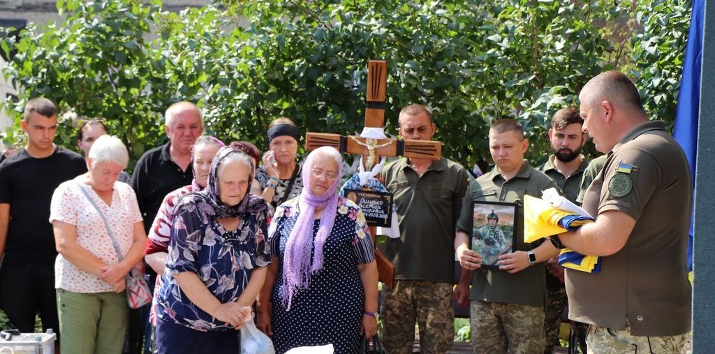 Капелан передає стяг родині, згідно з військовим чином поховання воїнів ЗСУ